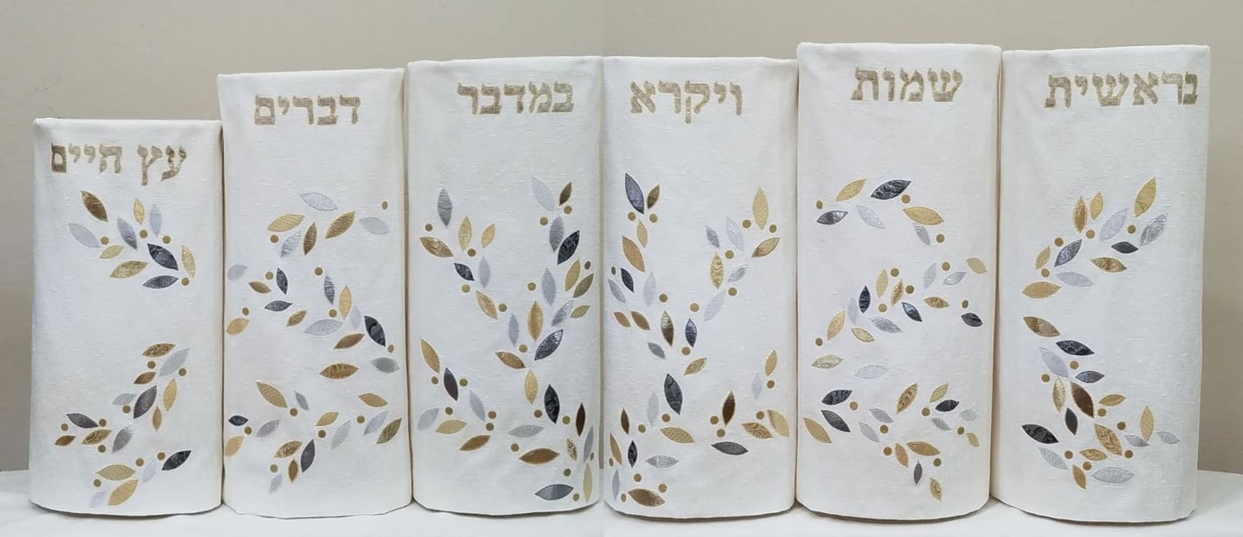 a set of white torah covers with golden leaves
